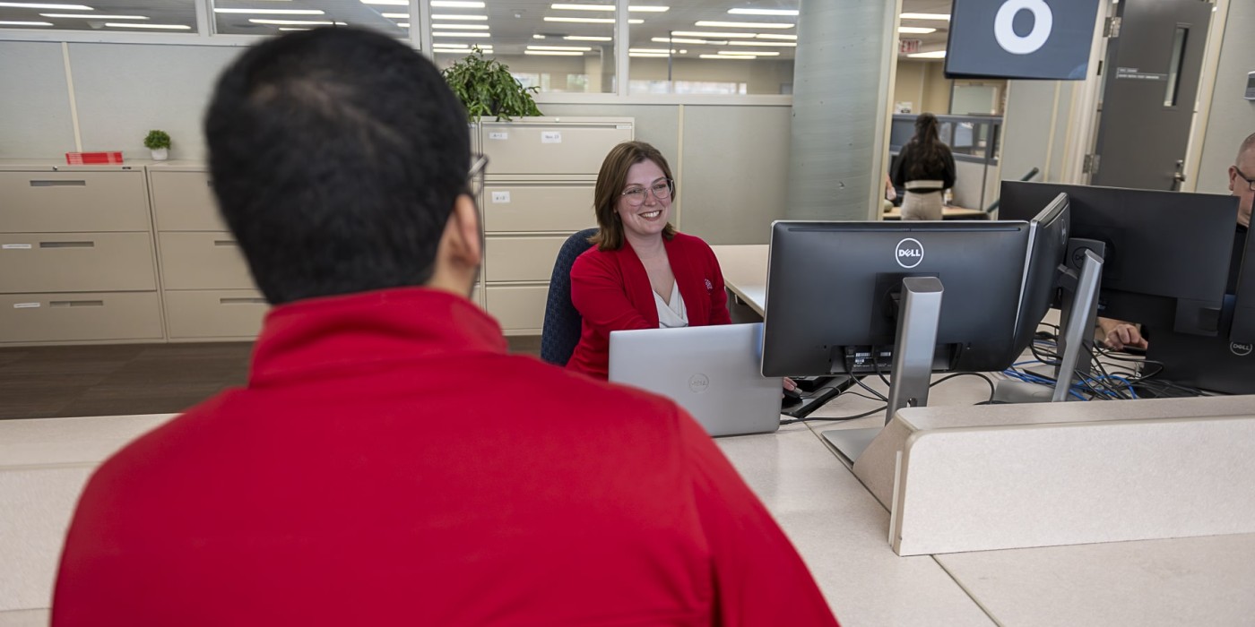 student talks to staff at desk in office of the registrar