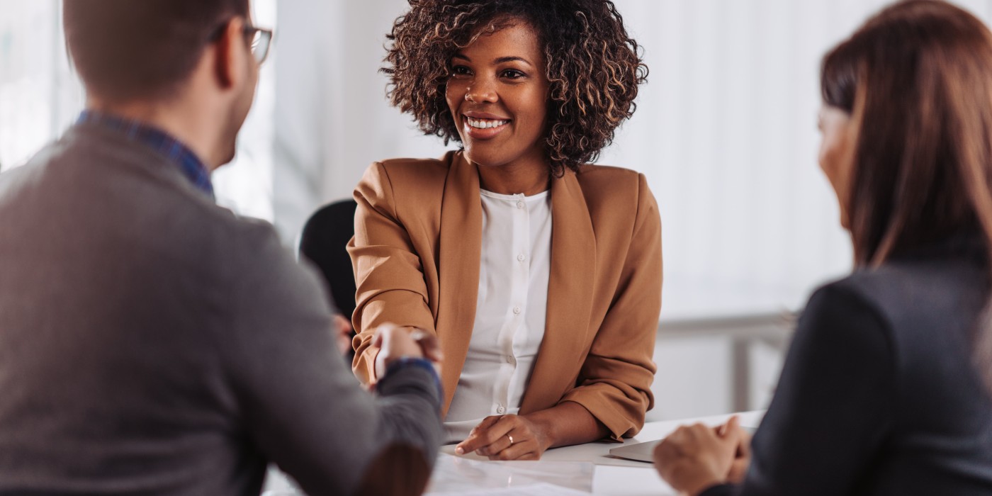 Professionals shake hands over desk with paperwork