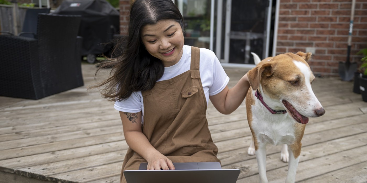 student sits on porch studying next to dog