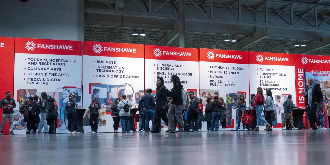 prospective students explore fanshawe programs in front of signs for areas of study