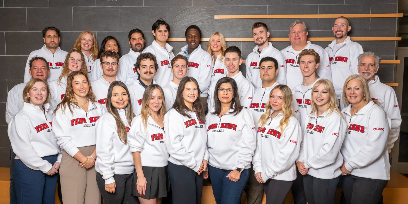 Students in white Fanshawe sweaters posting for a group photo.