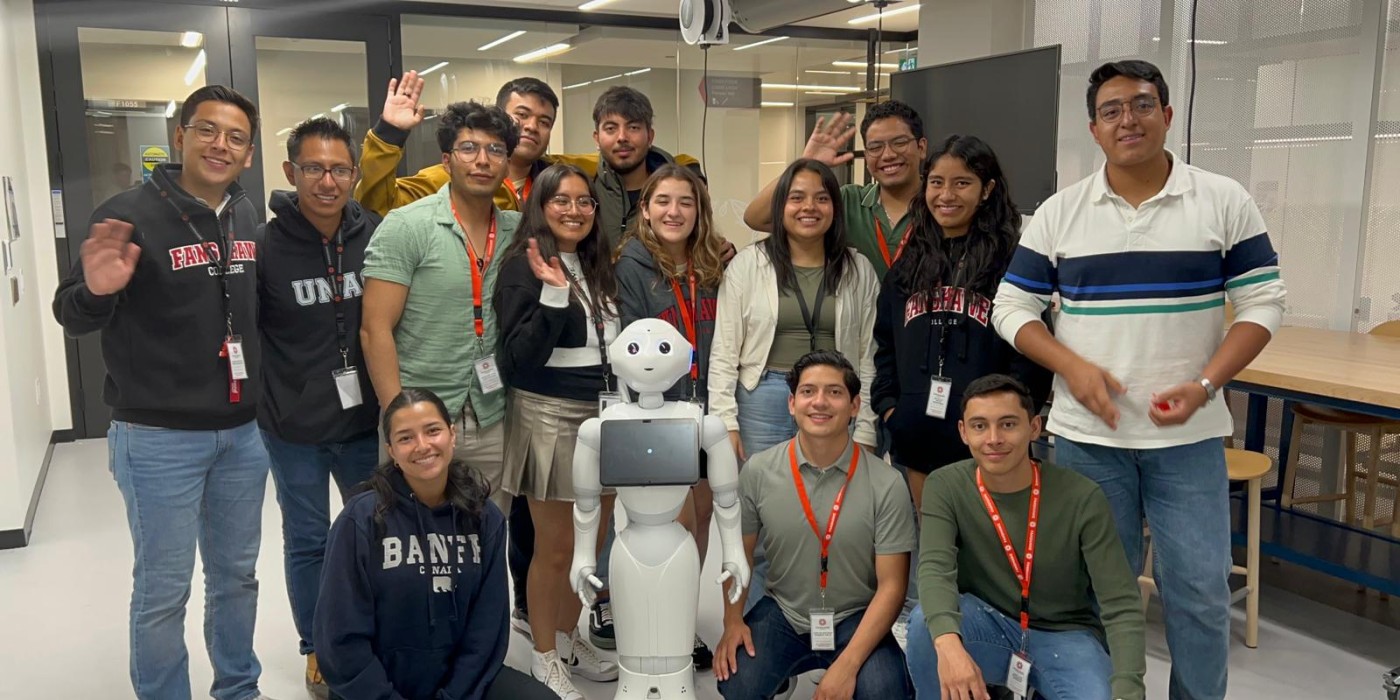 A group of student is taking a photo with a robot