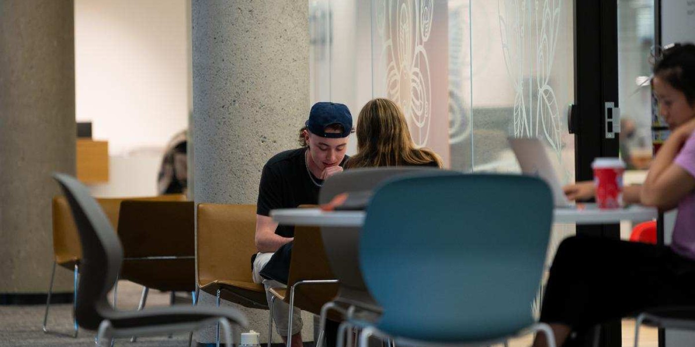 two Indigenous students chat together at summer dinner and paint night