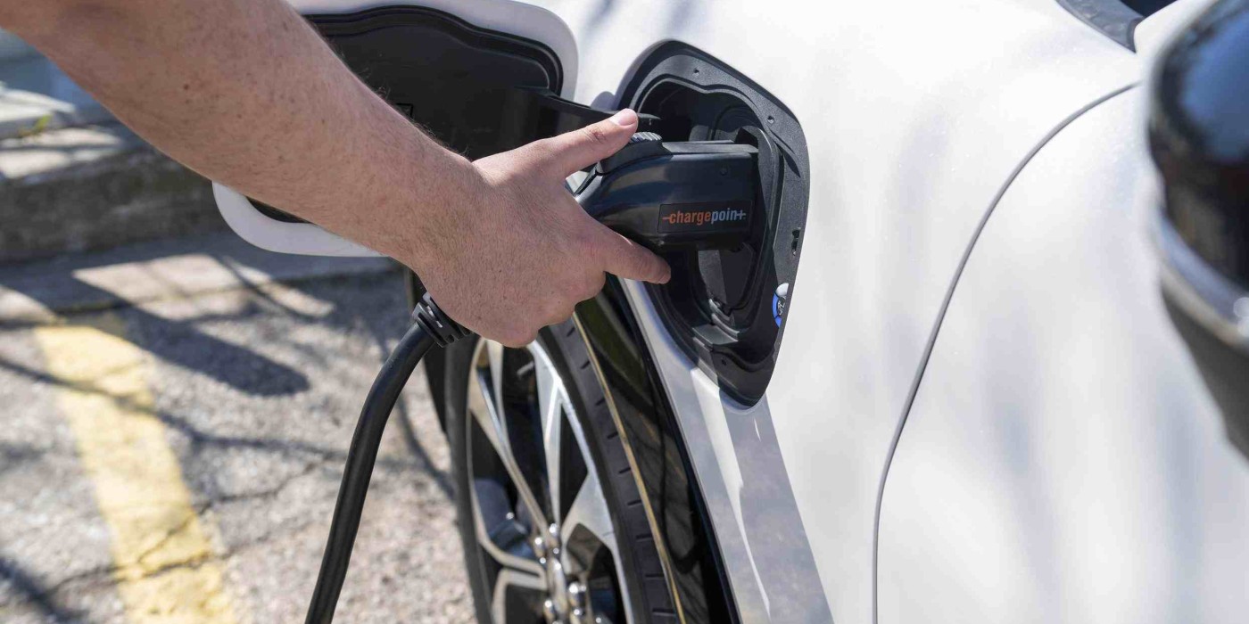 person plugs in Fanshawe's electric vehicle mustang