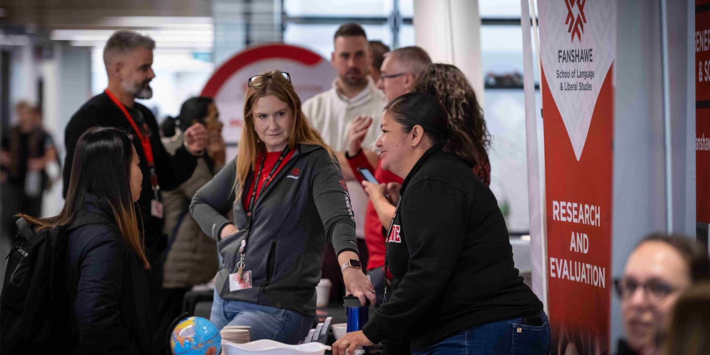 A Fanshawe booth set up at the pathway fair with a Fanshawe employee speaking to a student