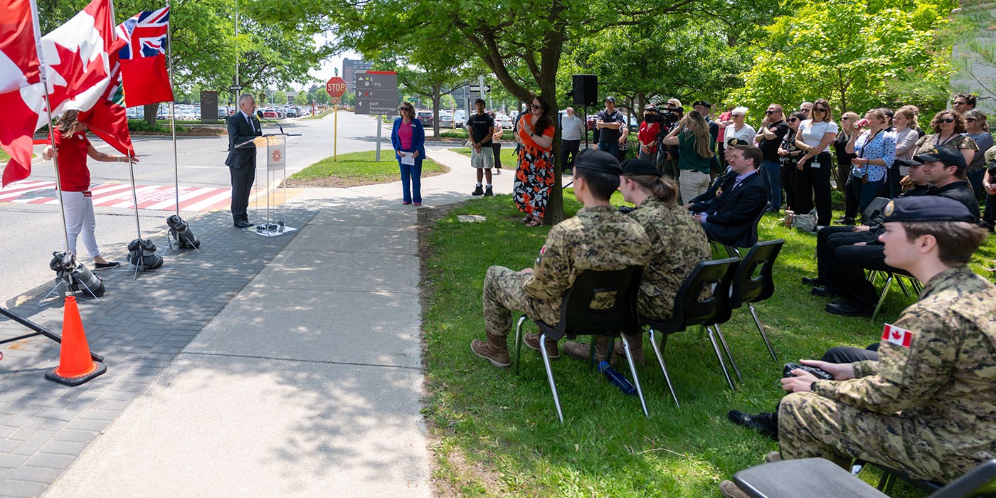 Peter Devlin speaks in front of crowd at military-connected college crosswalk opening