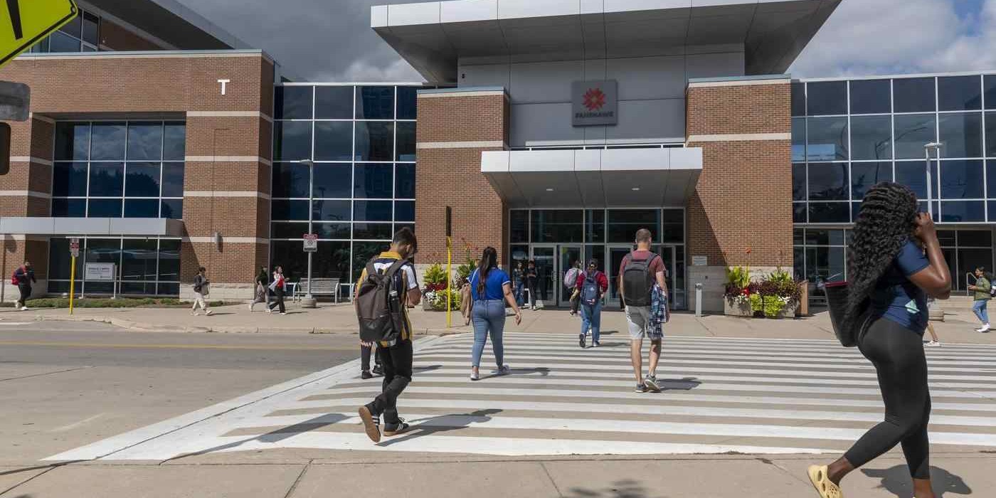 students walk across crosswalk in front of Fanshawe college
