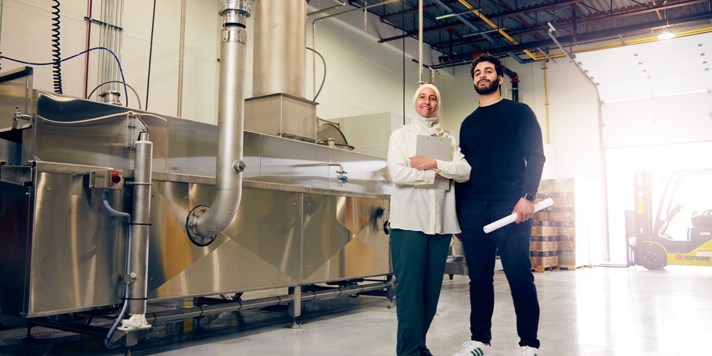 Photo of a women and a man posing for a photo in their factory