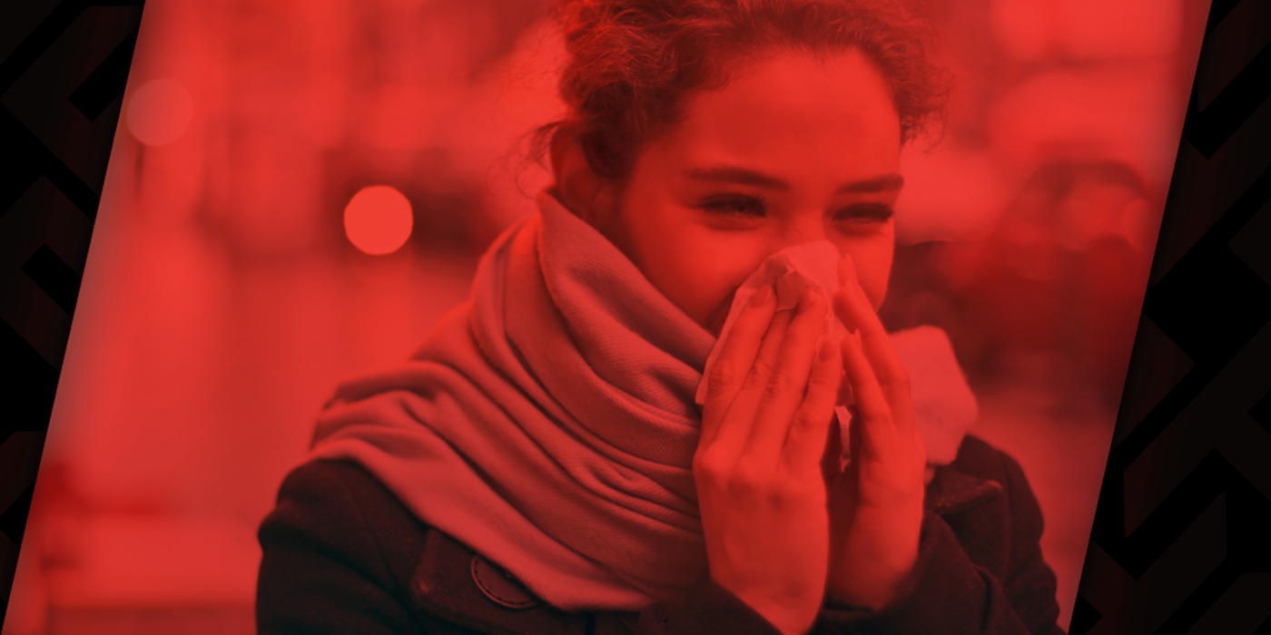 A young woman covers her face in a tissue while sneezing