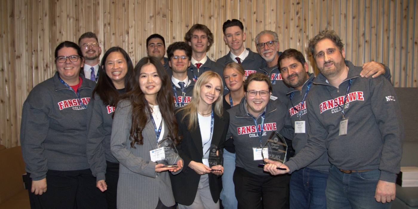 A group photo of smiling students and faculty holding first place trophies.
