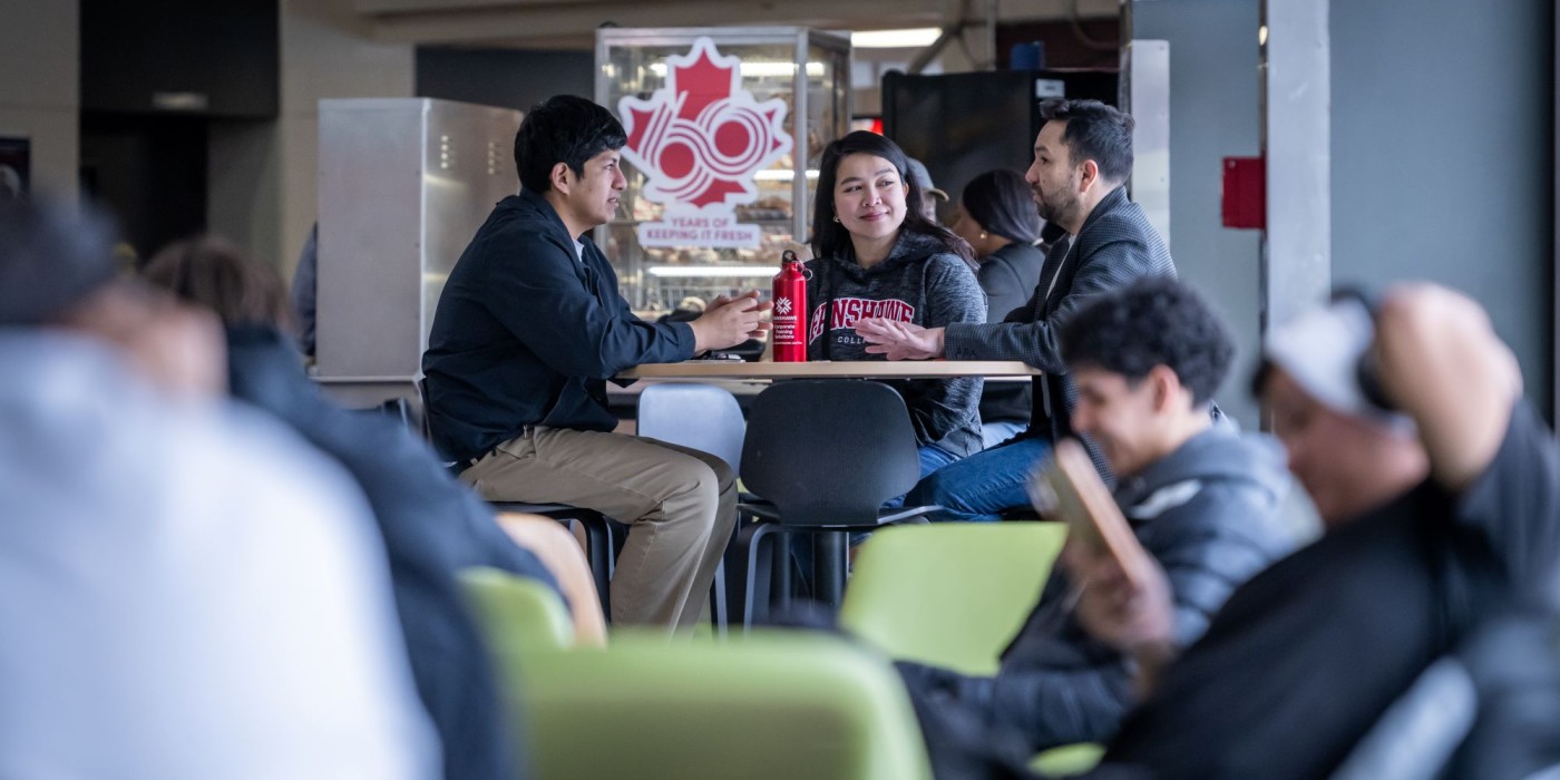 Three students sitting in a cafeteria at a table.