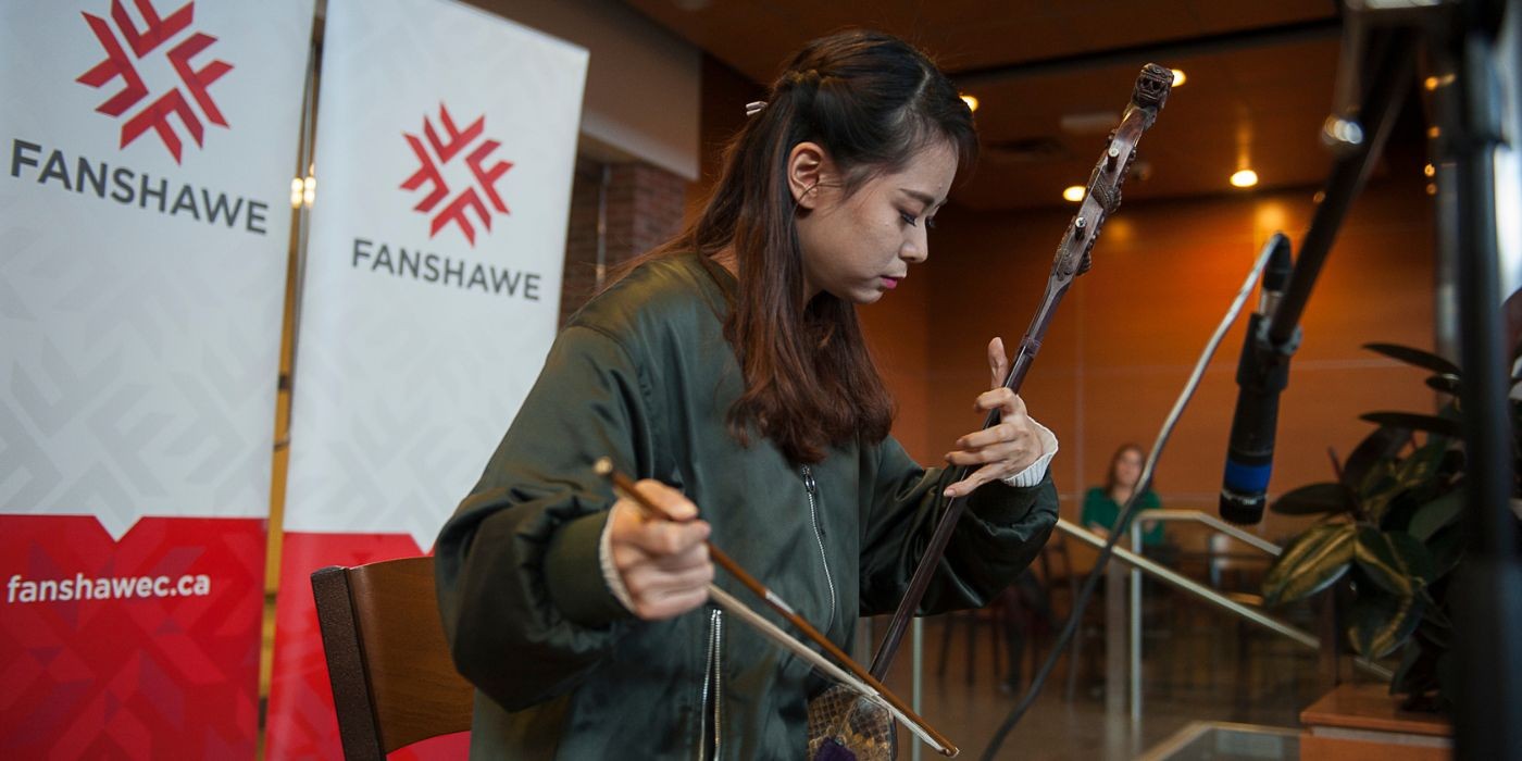 Asian students plays a traditional stringed instrument.