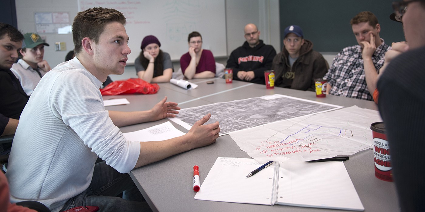 At the London Campus of Fanshawe College, a group sits around a table with maps and notes, engaged in a discussion for the GIS and Urban Planning program.