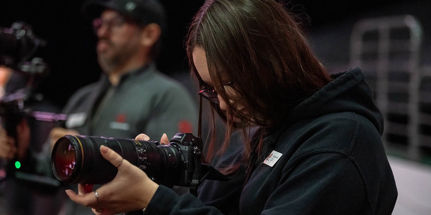 A photographer with a professional camera captures images at the Fanshawe College Convocation, held at Canada Life Place in London, Ontario.