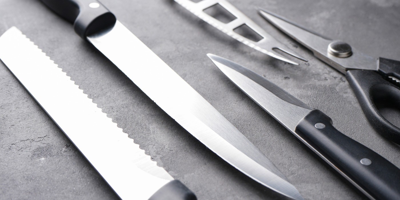 A bread knife, utility knife and paring knife, along with fish knife and scissors on a counter