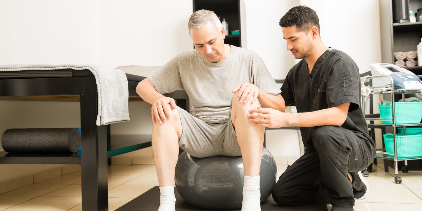 A physiotherapy practitioner works with a older gentleman on mobility exercises