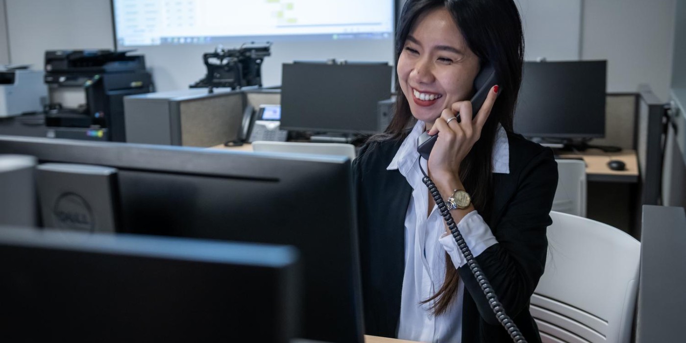Fanshawe employee answering a phone call and smiling while at their desk