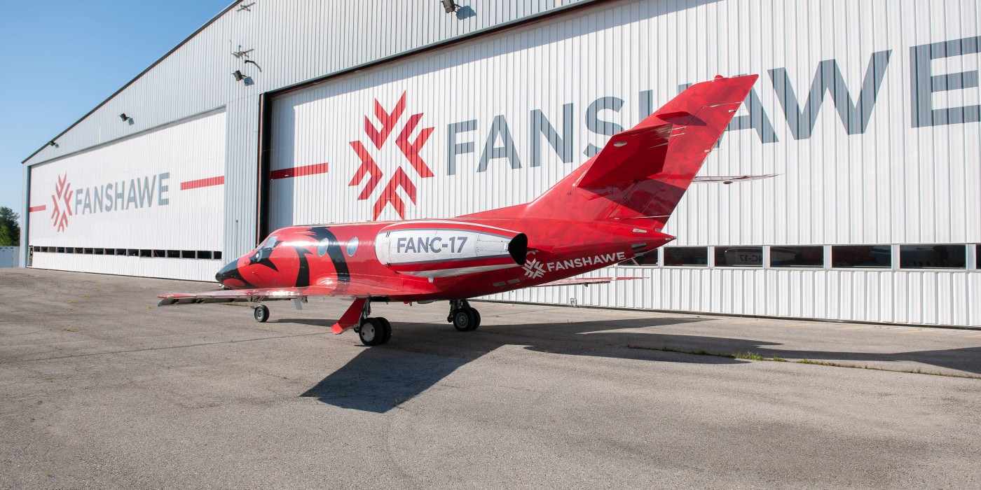A red and white jet, marked "FANC-17" and "Fanshawe," sits on the tarmac in front of the Aviation Centre, part of Fanshawe College's London Campus.