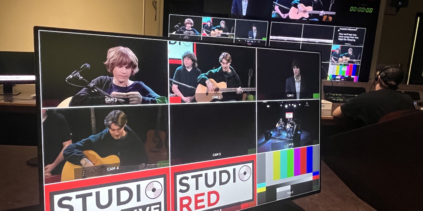 Control room monitors display multiple camera feeds during a live Studio Red Live music broadcast featuring performers on stage.