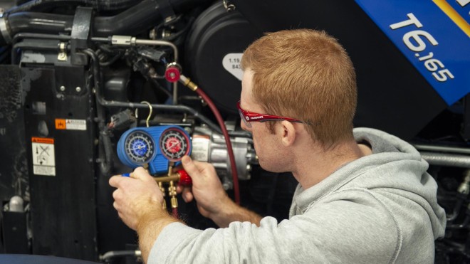 Agricultural Equipment Technician student checking gauge on machinery in shop at Fanshawe College