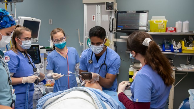 Group of 5 students practicing incubating on a fake patient