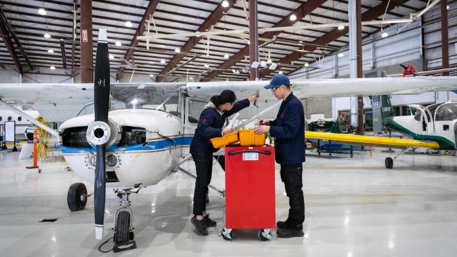 Two Aviation Technician Avionics Maintenance students working in front of airplane in Jazz Hangar at Fanshawe College