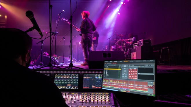 Student performing on stage with sound engineer on the side