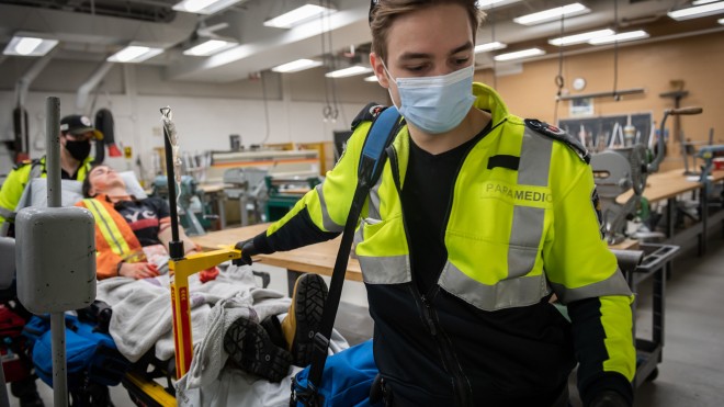 Paramedic student with practice patient on stretcher