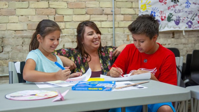 Child and Youth worker, chatting with two young people who are colouring