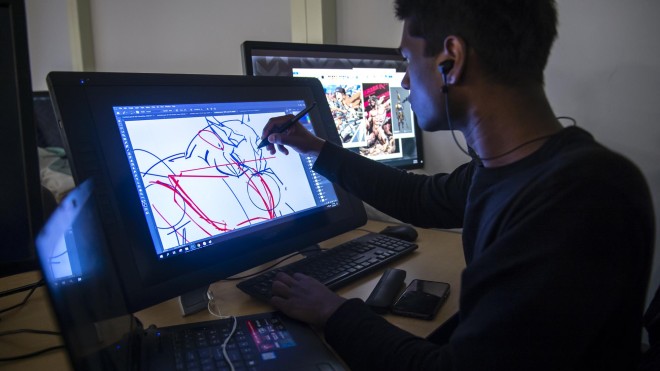 Student in computer lab, drawing a character on a display tablet