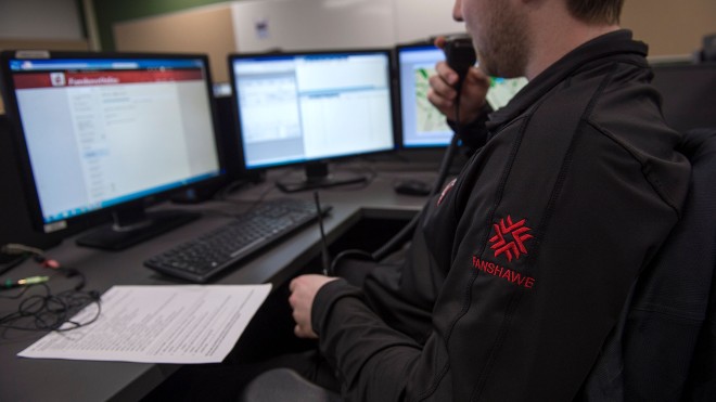 Guy sitting in front of screens with walkie talkie