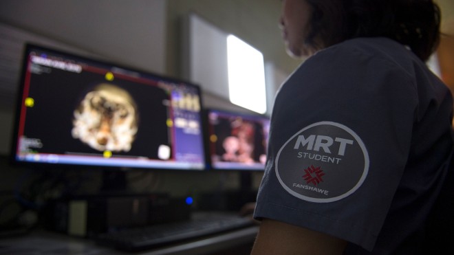 Student wearing scrubs and looking at x-rays on computer