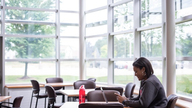 student sits at table in study space in residence