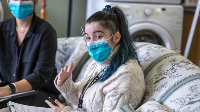 Nurse Aide sits on couch talking to employees in a facility