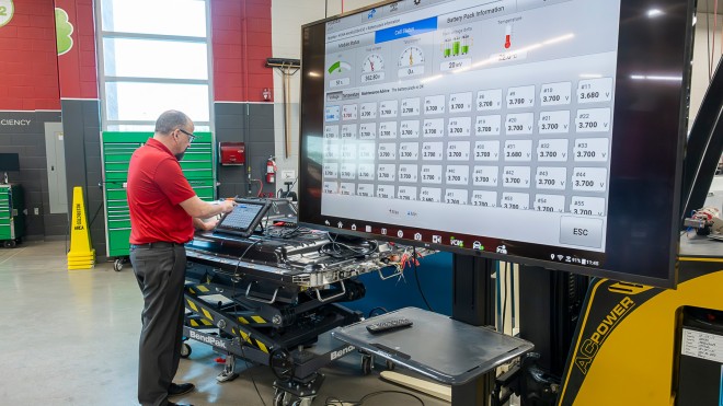 Green Vehicle Technician faculty member working on a car