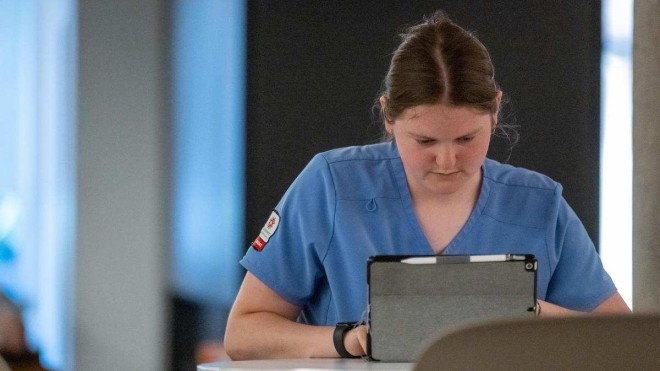 hospital worker types on tablet