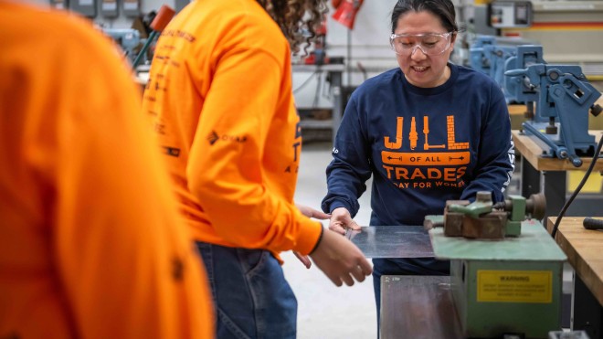 A female instructor guides a high school student through an activity during a Jill of All Trades event.
