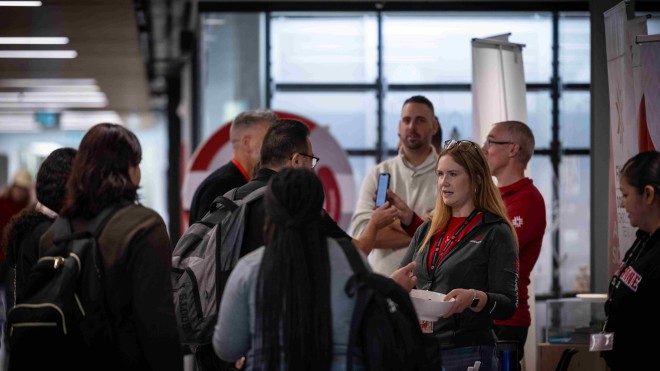 A Fanshawe employee speaking with a student in a crowded environment at the pathways fair