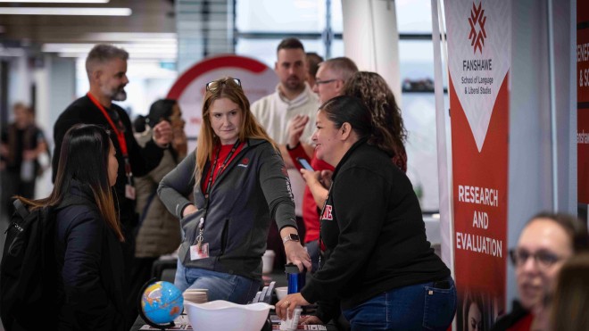 A Fanshawe booth set up at the pathway fair with a Fanshawe employee speaking to a student