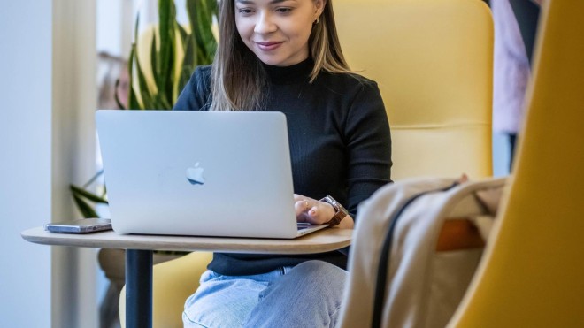 Photo of a student sitting at a work space on their laptop in Innovation Village