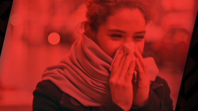 A young woman covers her face in a tissue while sneezing