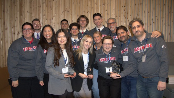 A group photo of smiling students and faculty holding first place trophies.