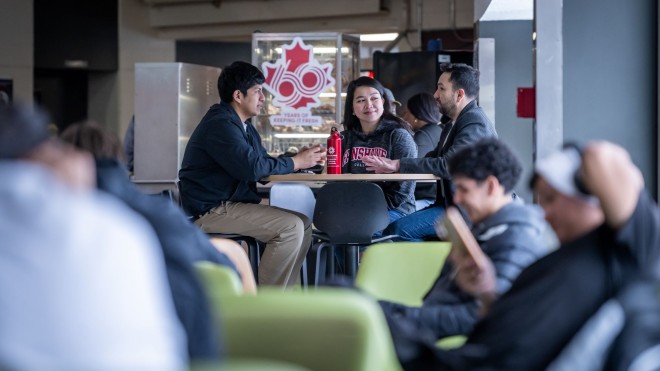 Three students sitting in a cafeteria at a table.