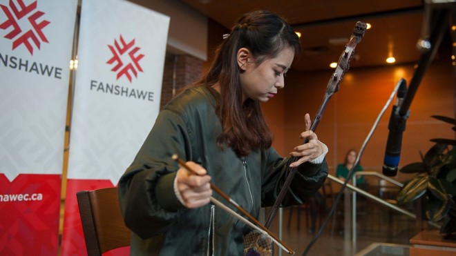 Asian students plays a traditional stringed instrument.