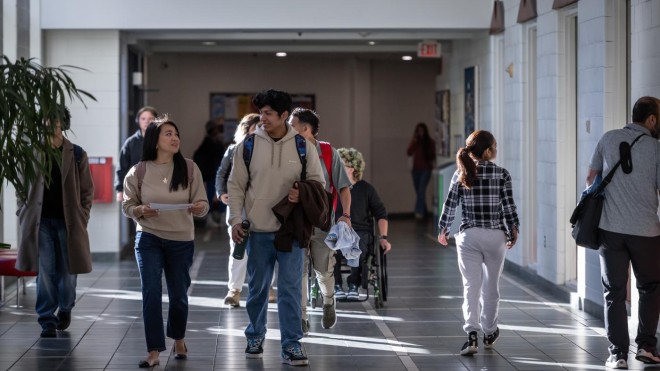 Students walk through a hallway at Fanshawe College's London Campus, with a fire extinguisher visible on the wall.
