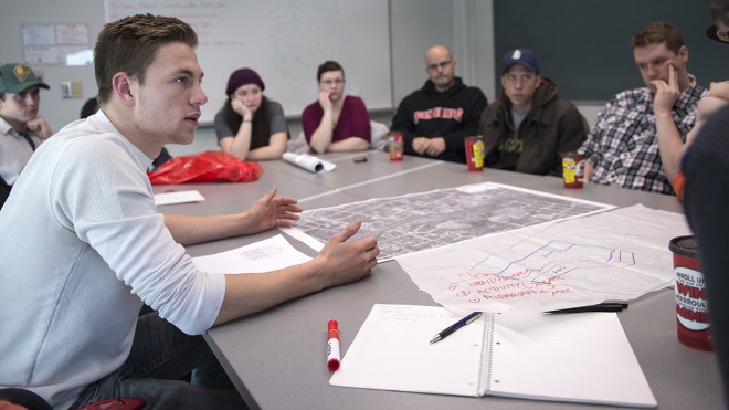 At the London Campus of Fanshawe College, a group sits around a table with maps and notes, engaged in a discussion for the GIS and Urban Planning program.