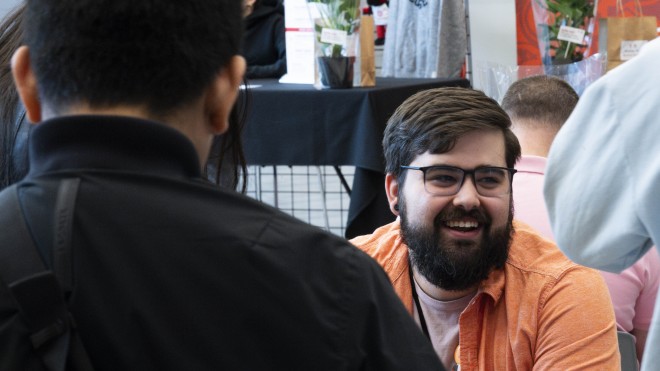 Image of a sitting and smiling man with a beard at a Fanshawe student event.