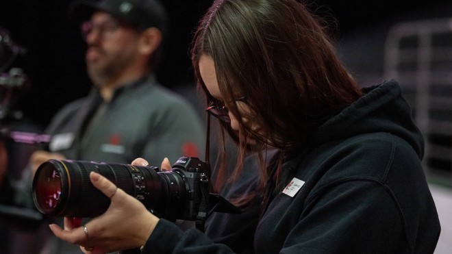 A photographer with a professional camera captures images at the Fanshawe College Convocation, held at Canada Life Place in London, Ontario.
