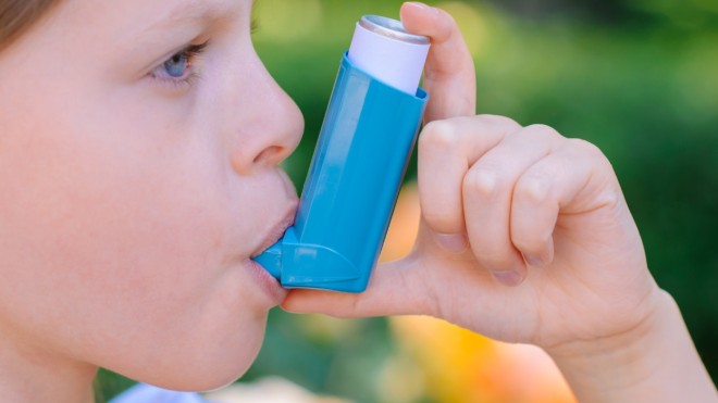 A young child makes use of a Metered Dose Inhaler to aid with breathing