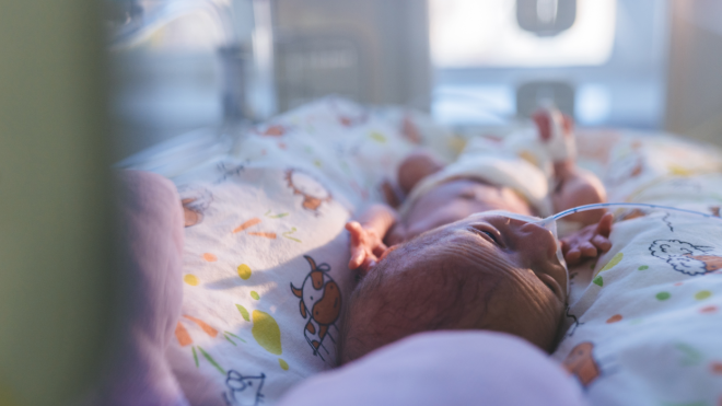 A baby inside an incubator in the NICE with wires attached to them